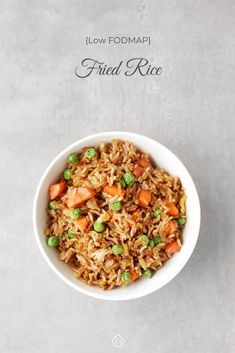 a white bowl filled with fried rice and veggies on top of a table