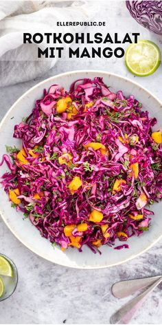 a white bowl filled with red cabbage slaw next to sliced limes and lemon wedges