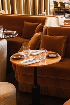 a table with two glasses on it in front of a couch and some other furniture