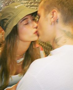 a man and woman kissing each other while wearing hats