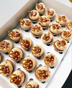 a box filled with cupcakes covered in frosting and pretzel decorations