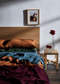 a bedroom with a bed, side table and pictures on the wall above it is shown