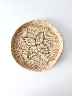 a small woven plate with two flowers on the front and one flower in the middle