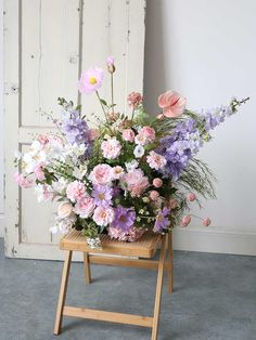 a wooden stand holding a bunch of flowers in it's center and an open door behind it