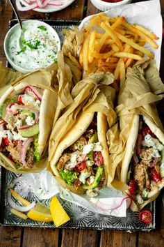 three pita sandwiches and fries on a tray