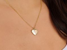 Embrace the delicate iridescence of the Mother of Pearl Heart Necklace, a piece that radiates with soft luminescence. Encased in a slender gold embrace, this heart-shaped pendant captures the gentle, nurturing essence of motherhood and the calming touch of the ocean's treasure. It's a versatile accessory that pairs as beautifully with daytime looks as it does with evening attire, making it a precious gift or cherished addition to your jewelry collection. Pendants are made of Natural Mother of Pe Delicate Gold Heart Necklace With Pearl Pendant, Feminine Gold Heart Necklace Gift, Gold Feminine Heart Necklace, Feminine Gold Heart Necklace, Delicate Heart Necklace With Pearl Pendant, Delicate Pearl Pendant Heart Necklace, Heart Shaped Pearl Pendant Necklace For Mother's Day, Mother's Day Heart Necklace With Pearl Pendant, Mother's Day Heart Shaped Pearl Pendant Necklace