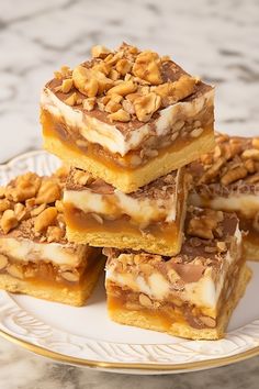 several pieces of dessert sitting on top of a white and gold plate next to a marble counter