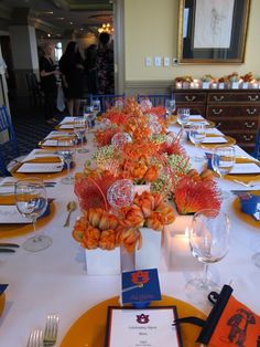 the table is set for an event with orange flowers