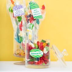 there are many candies in the glass vases on the table and one is labeled gummy bears