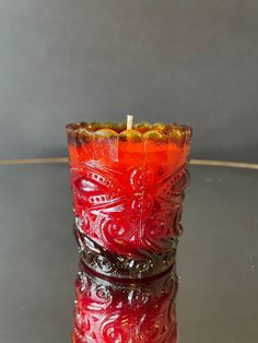 a red candle sitting on top of a glass table