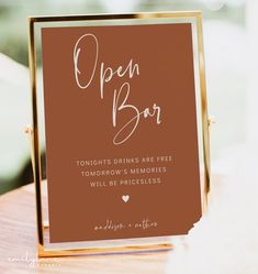 an open bar sign sitting on top of a wooden table