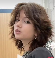 a woman with short hair and piercings standing in front of a wall