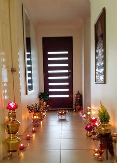 a hallway with candles and potted plants on the floor in front of a door