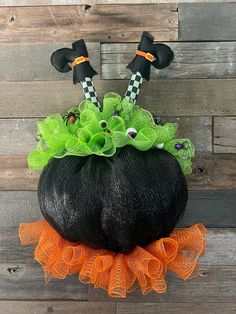 a black pumpkin decorated with green and orange decorations