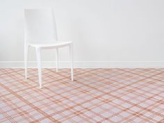 a white chair sitting on top of a checkered floor next to a white wall