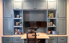 a home office with built in cabinets and desk