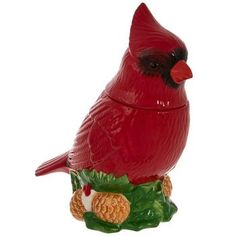 a red bird sitting on top of a pine cone