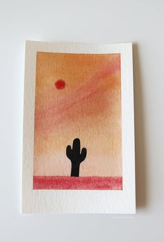 a card with a painting of a cactus in the desert on it's side