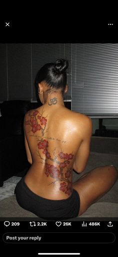 a woman sitting on the floor with her back to the camera and tattoos on her body