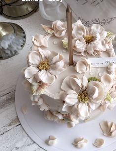 a white cake with flowers on it sitting on top of a table next to other items