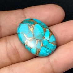 a person is holding a turquoise stone in their hand