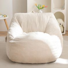 a white bean bag chair sitting on top of a floor next to a small table