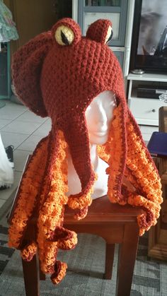 a crocheted octopus hat on top of a wooden table next to a white mannequin's head