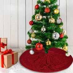 a christmas tree with presents under it and a red blanket on the floor next to it