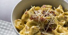 a close up of a bowl of food with cheese and bacon in it on a checkered table cloth