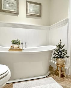 a white bath tub sitting in a bathroom next to a toilet and a christmas tree