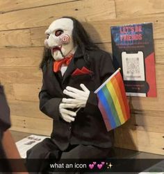 a creepy doll sitting on top of a table next to a rainbow flag and book