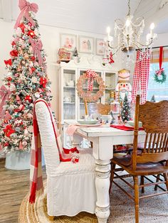 a christmas tree is in the corner of a room with chairs and a dining table