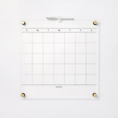 a white board with gold studs on the sides and a calendar attached to it