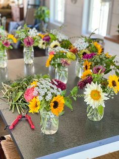 several vases filled with different colored flowers on a table in a kitchen or dining room