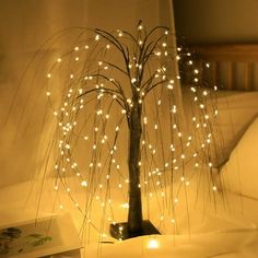 a lighted tree on a bed with white lights in the middle and branches sticking out of it