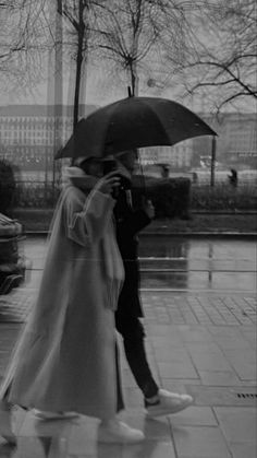 a man and woman walking in the rain under an umbrella