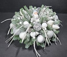 an arrangement of christmas decorations on a black tablecloth with silver and white ornaments in the center