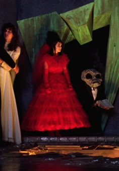 two women in red dresses standing next to each other with masks on their heads and hands