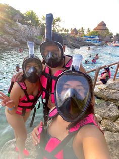 two women wearing scuba gear and snorkels posing for a photo in the water