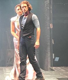 a man and woman standing on stage in front of each other with their arms around one another