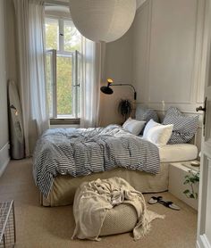 a bed room with a neatly made bed next to a window and a large lamp