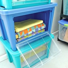 a stack of folded towels sitting on top of a blue shelf next to a plastic container