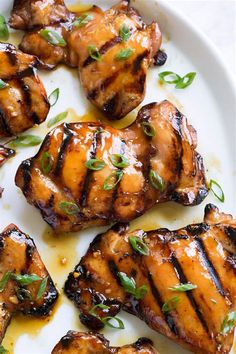 grilled chicken on a white plate topped with green garnish and parsley