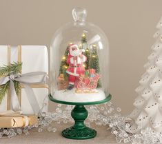 a christmas scene under a glass clochel with santa clause and presents underneath it