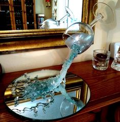 a wine glass being filled with water from a faucet on top of a table