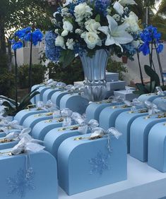 many blue boxes with white flowers in them are on display at a wedding or other event