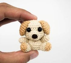 a hand holding a small crocheted dog