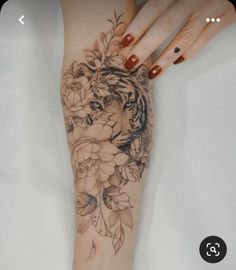 a woman's arm with a tiger and flowers tattoo on it