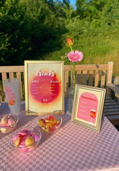 a table topped with plates and bowls filled with candy next to a framed menu on top of a checkered table cloth