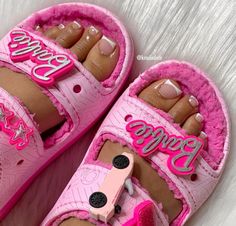 a pair of pink shoes with the word barbie written on them and two pairs of feet